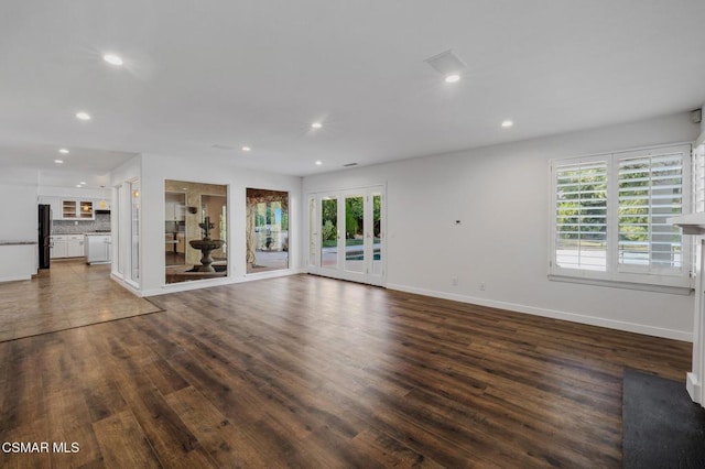 unfurnished living room with dark hardwood / wood-style floors and french doors