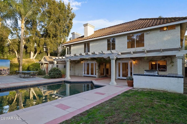 rear view of house featuring exterior kitchen, a pergola, a patio, and french doors