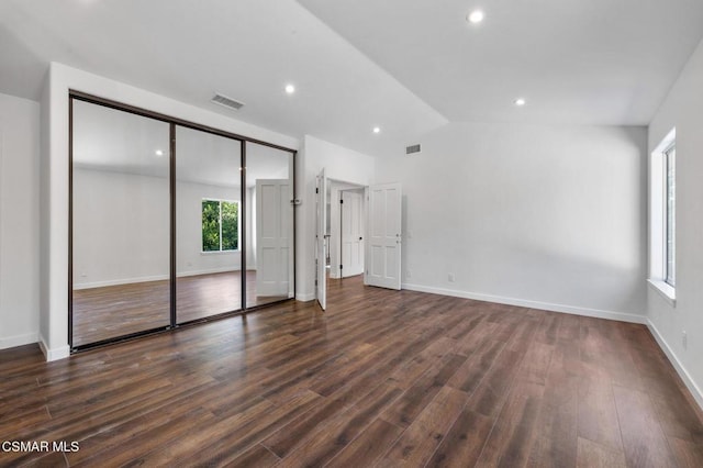 unfurnished bedroom featuring vaulted ceiling, dark hardwood / wood-style floors, and a closet