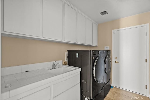 washroom with sink, cabinets, independent washer and dryer, and light tile patterned flooring