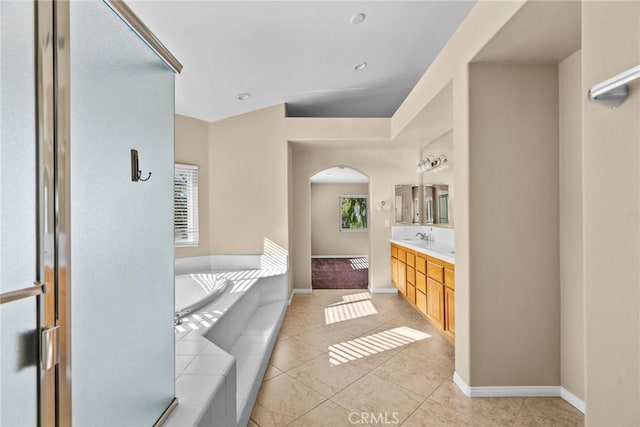 bathroom with tile patterned floors, vanity, tiled bath, and plenty of natural light