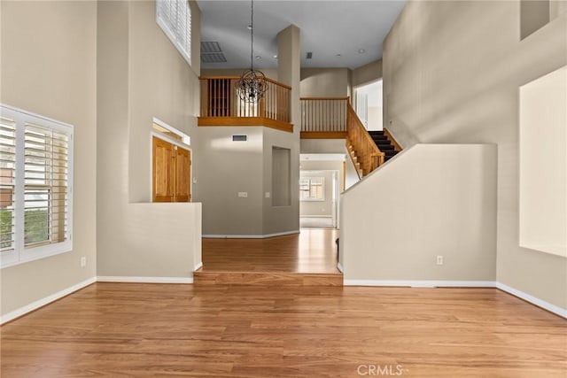 entryway with a towering ceiling, an inviting chandelier, and light wood-type flooring