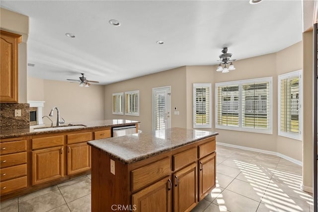 kitchen with sink, light tile patterned floors, light stone counters, a kitchen island, and stainless steel dishwasher