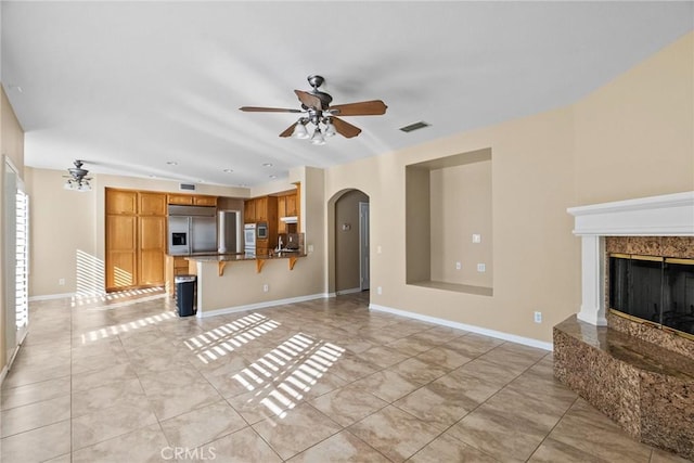 unfurnished living room with a fireplace and ceiling fan