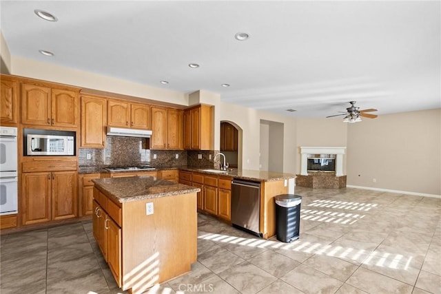 kitchen featuring stainless steel appliances, a center island, and dark stone counters