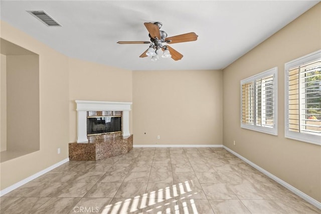 unfurnished living room featuring a premium fireplace and ceiling fan