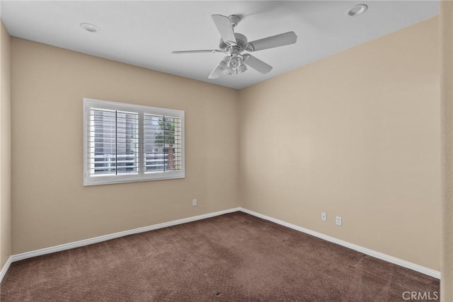 empty room featuring ceiling fan and dark carpet