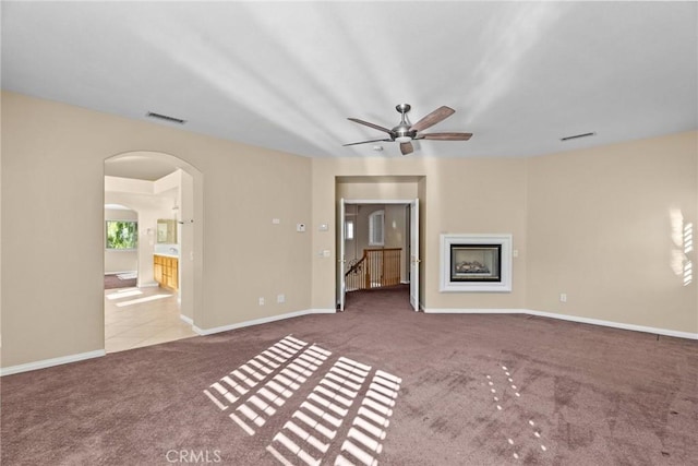 unfurnished living room featuring ceiling fan and carpet flooring