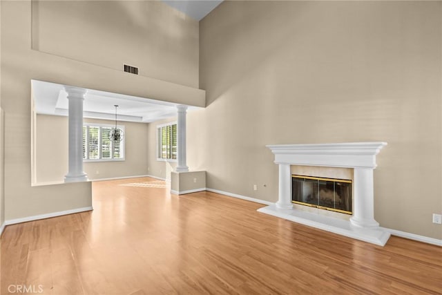 unfurnished living room with ornate columns and wood-type flooring