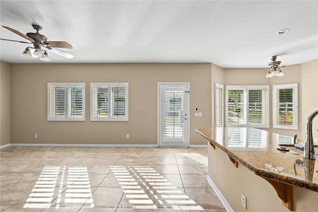 kitchen featuring light tile patterned floors, ceiling fan, and stone counters