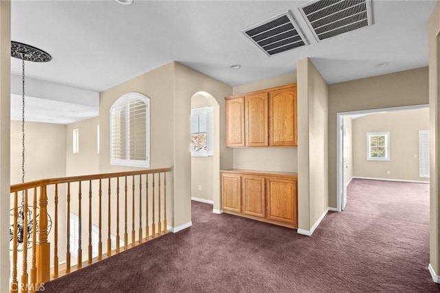 hallway with dark colored carpet