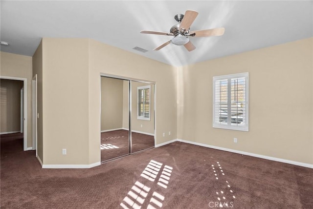 unfurnished bedroom with dark carpet, ceiling fan, and a closet