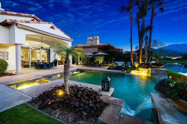 pool at dusk featuring a patio area and a mountain view