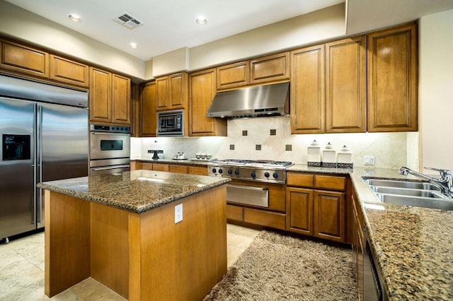 kitchen with sink, a center island, stone counters, and built in appliances