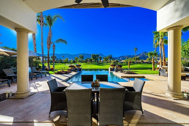 view of pool with a mountain view, ceiling fan, a patio, and a yard