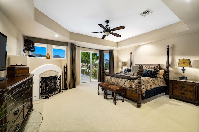 carpeted bedroom featuring a raised ceiling, ceiling fan, and access to outside