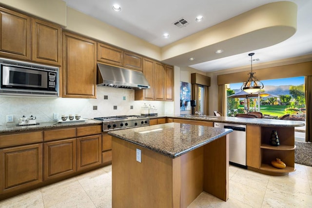 kitchen with stone counters, hanging light fixtures, a kitchen island, kitchen peninsula, and stainless steel appliances