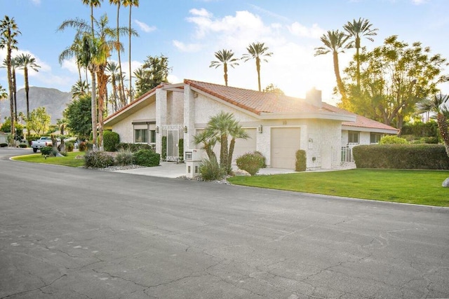 view of front of home featuring a mountain view, a front yard, and a garage