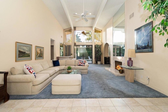 living room featuring a fireplace, a towering ceiling, light tile patterned floors, and ceiling fan