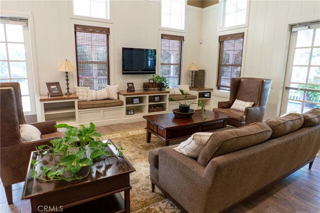 living room with wood-type flooring, a high ceiling, and plenty of natural light