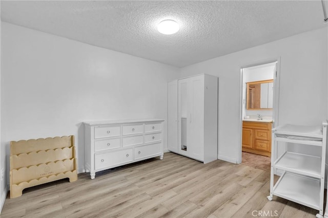 bedroom featuring connected bathroom, a textured ceiling, and light hardwood / wood-style floors