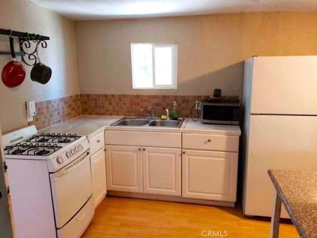 kitchen featuring sink, white appliances, light hardwood / wood-style flooring, white cabinetry, and tasteful backsplash