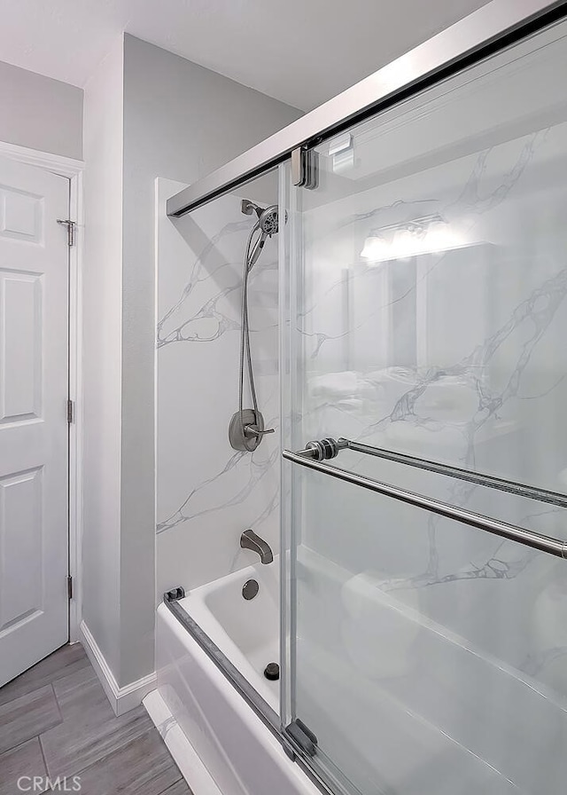 bathroom featuring combined bath / shower with glass door