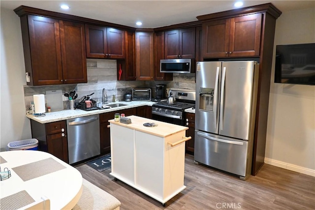 kitchen featuring stainless steel appliances, wood-type flooring, sink, and tasteful backsplash