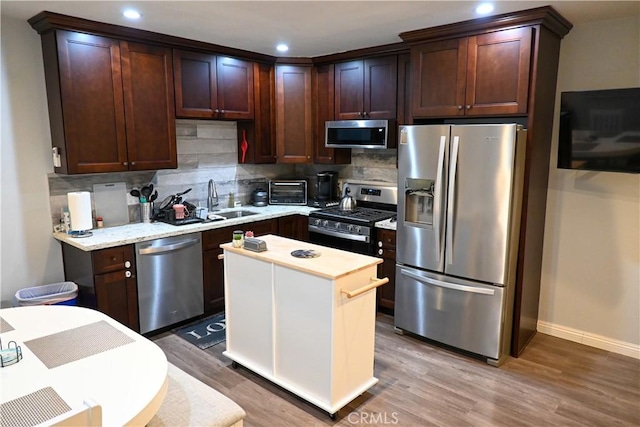 12530 Birch Ave, Hawthorne, CA 90250 - kitchen featuring appliances with stainless steel finishes, tasteful backsplash, light wood-style flooring, recessed lighting, and dark brown cabinets