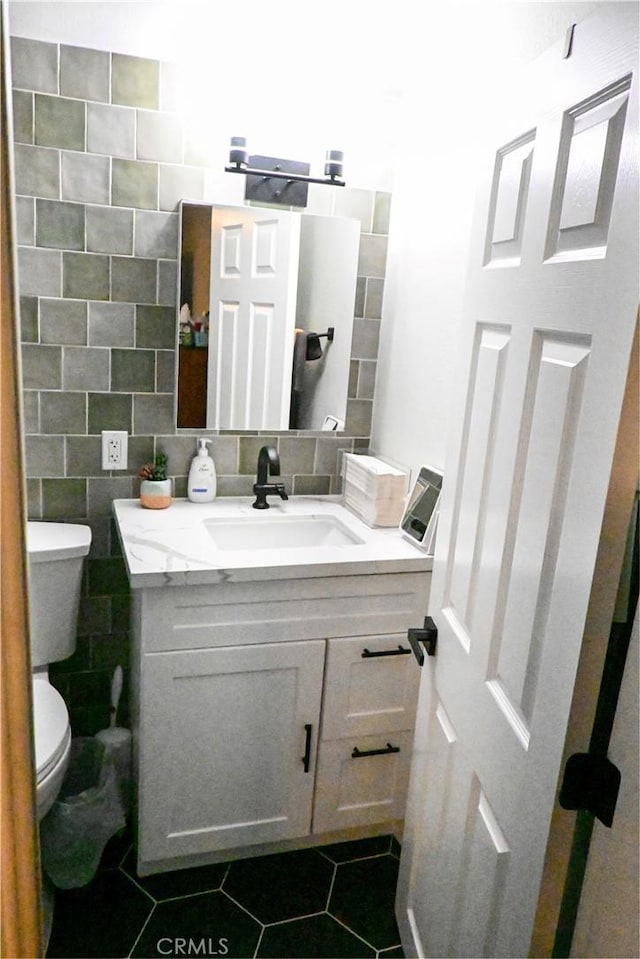 bathroom with tile patterned floors, toilet, vanity, and tile walls