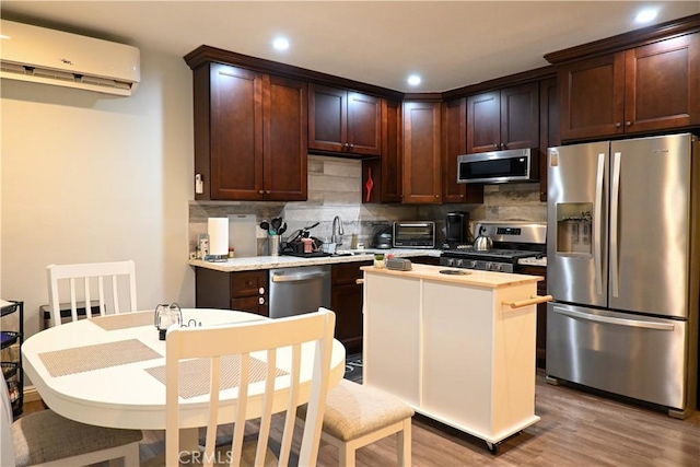 kitchen featuring a wall mounted air conditioner, a center island, light hardwood / wood-style flooring, appliances with stainless steel finishes, and backsplash