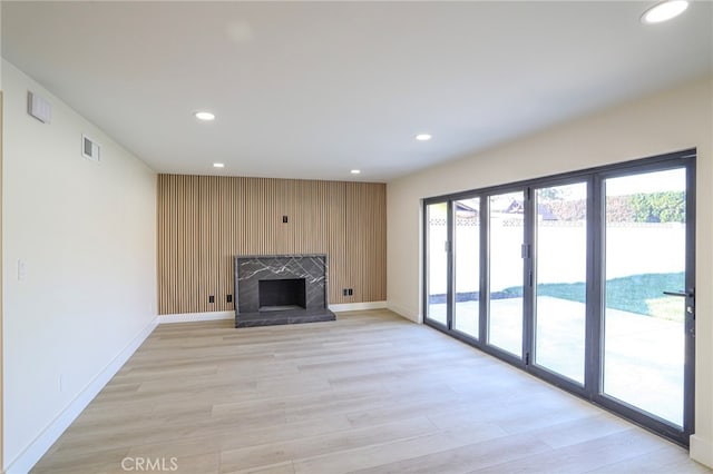 unfurnished living room with light hardwood / wood-style floors, a water view, and a fireplace