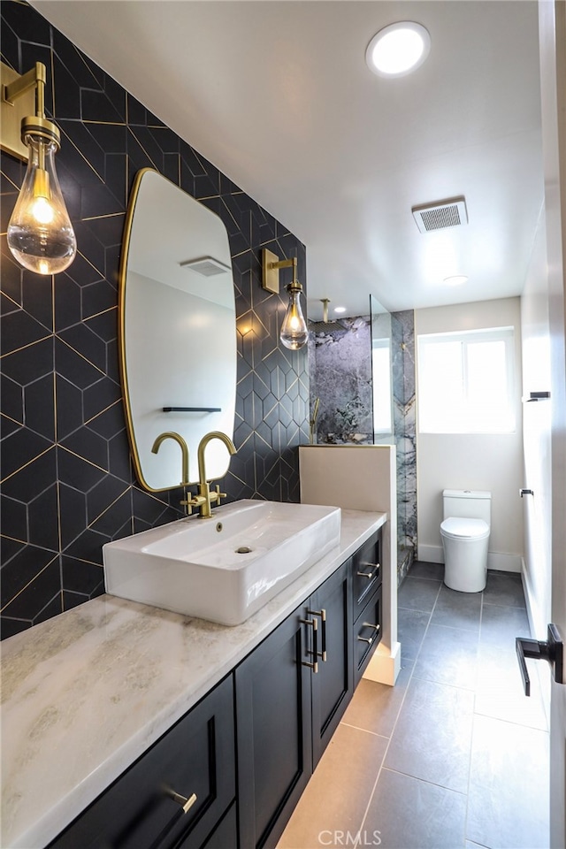 bathroom featuring toilet, vanity, tile patterned floors, and tile walls