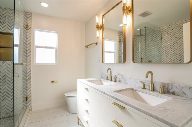 bathroom featuring vanity, toilet, a wealth of natural light, and tiled shower