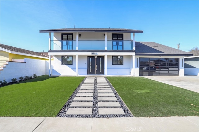 view of front of house featuring a front yard, a balcony, and a garage