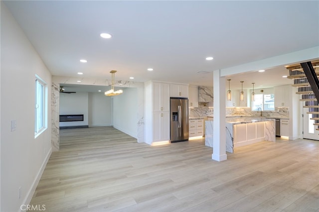 kitchen with backsplash, white cabinets, light hardwood / wood-style flooring, and appliances with stainless steel finishes