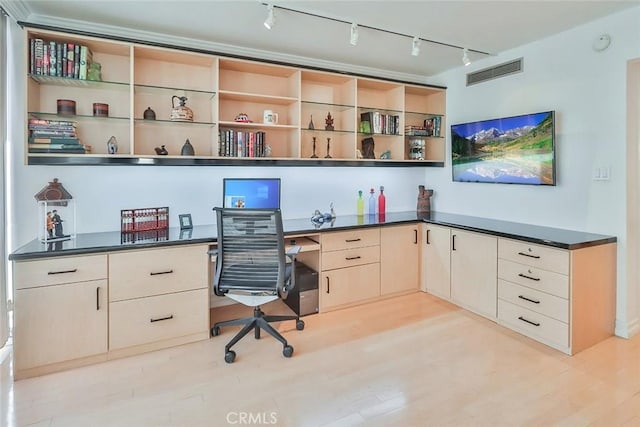 office space with built in desk and light hardwood / wood-style flooring