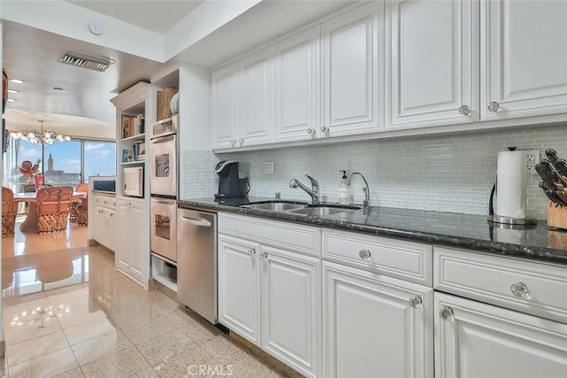 kitchen with white cabinets, dark stone counters, decorative backsplash, and sink