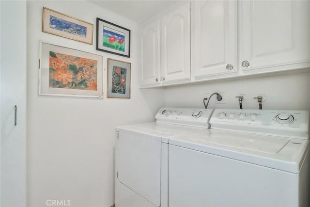 clothes washing area featuring separate washer and dryer and cabinets