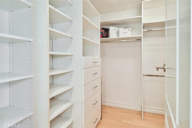 walk in closet with light hardwood / wood-style floors