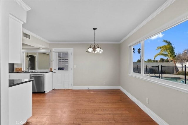 unfurnished dining area featuring crown molding, a chandelier, and light wood-type flooring