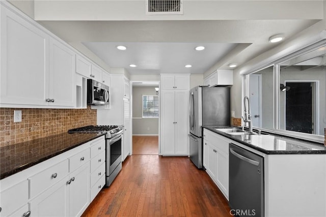 kitchen with tasteful backsplash, white cabinetry, appliances with stainless steel finishes, and dark wood-type flooring