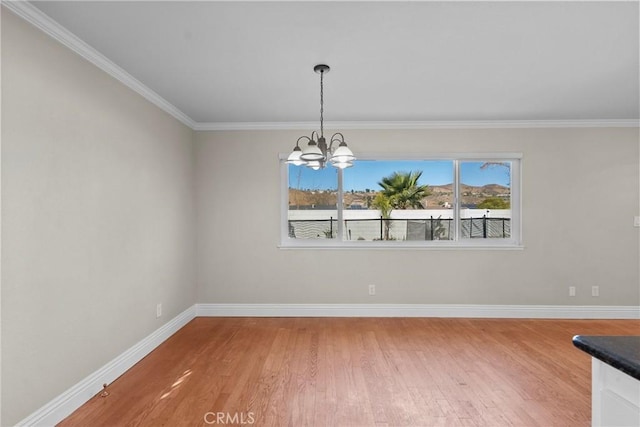 unfurnished dining area with a notable chandelier, crown molding, and hardwood / wood-style floors