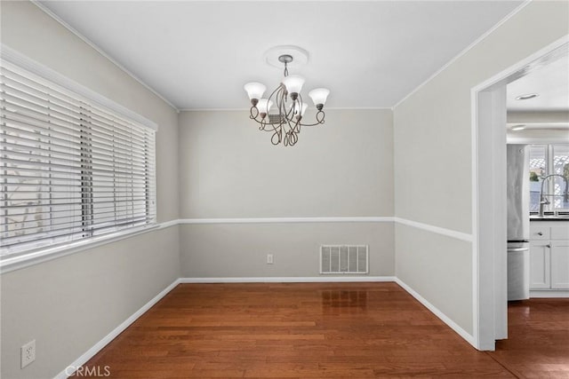 unfurnished dining area featuring sink, a notable chandelier, and dark wood-type flooring