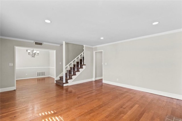 spare room featuring wood-type flooring, ornamental molding, and a notable chandelier