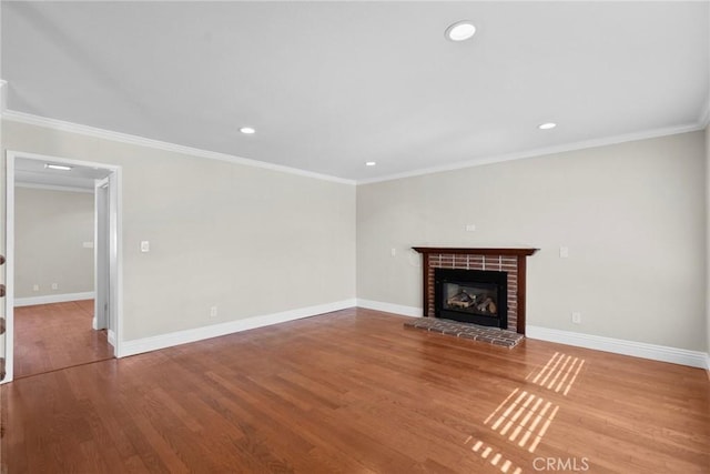 unfurnished living room with crown molding, a brick fireplace, and wood-type flooring