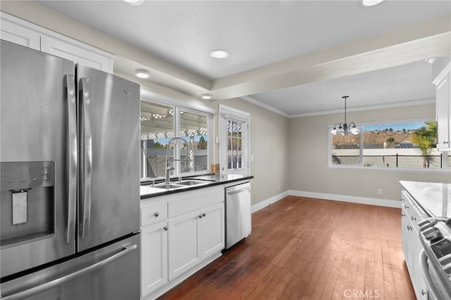 kitchen with stainless steel appliances, white cabinetry, hanging light fixtures, and sink