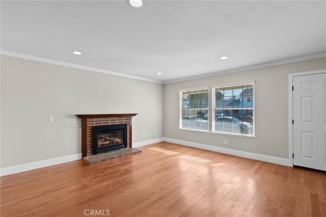 unfurnished living room featuring a brick fireplace, crown molding, and light wood-type flooring