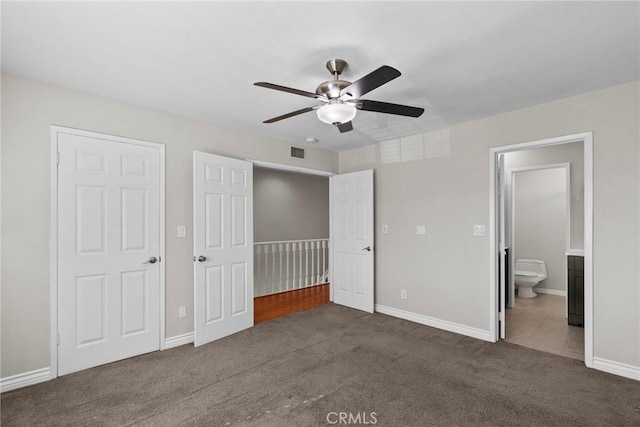 unfurnished bedroom with dark carpet, connected bathroom, and ceiling fan