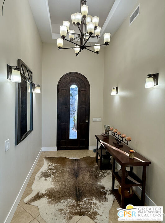 entrance foyer featuring a towering ceiling, a notable chandelier, and light tile patterned flooring